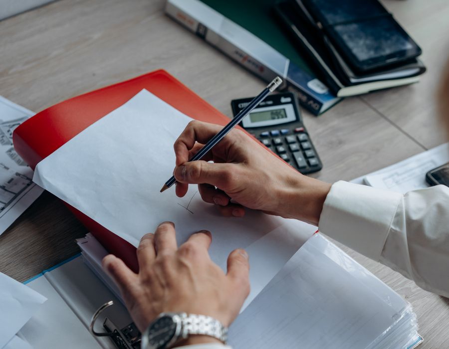 Vista cenital de manos trabajando con una carpeta, documentos y una calculadora
