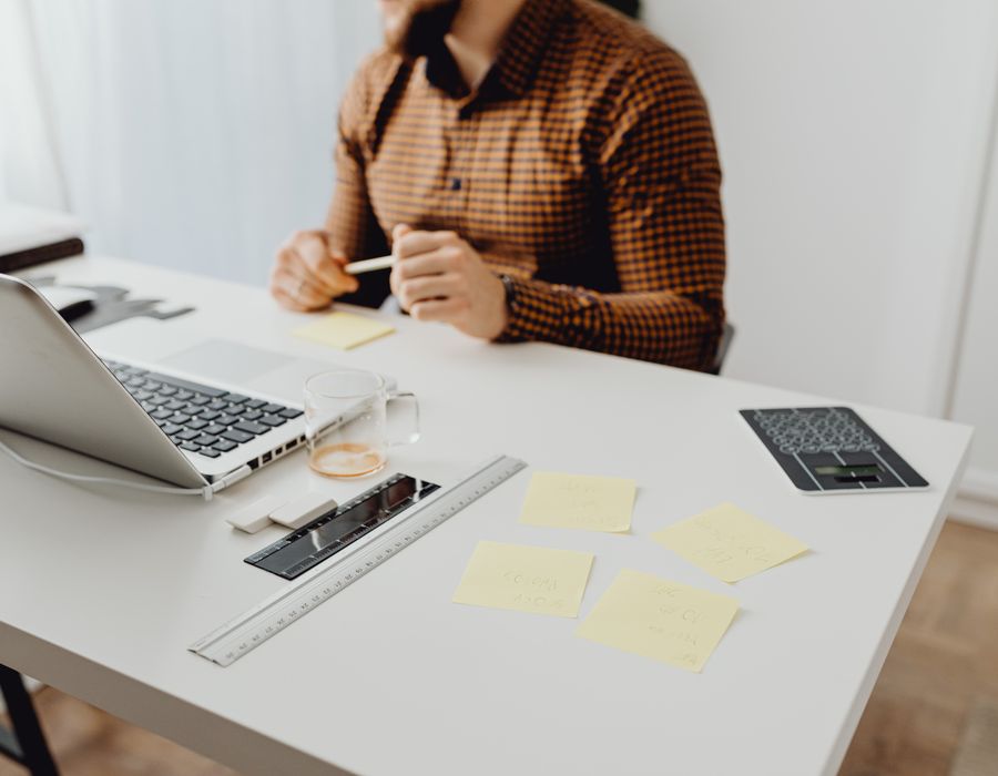 Escritorio claro con un computador portátil abierto, notas adhesivas y una calculadora